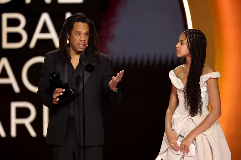 Picture: Jay Z accepting an honor, with his daughter Blue Ivy at his side, at Grammy Awards